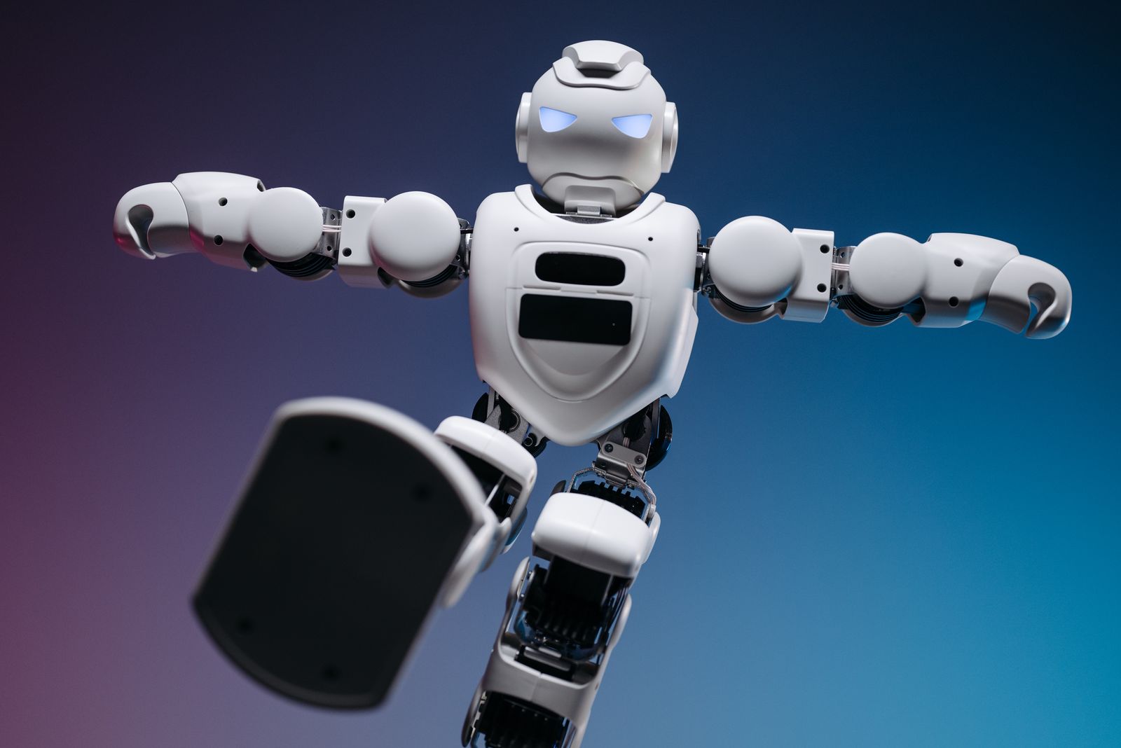 Robot humanoide de pie en un almacén industrial moderno con estanterías al fondo.
