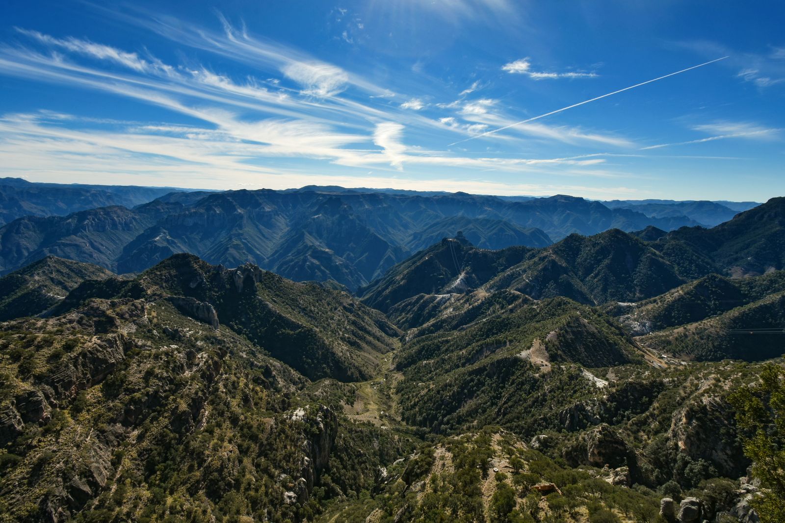 Mina de cobre a cielo abierto con camiones y terrazas de roca bajo un cielo despejado