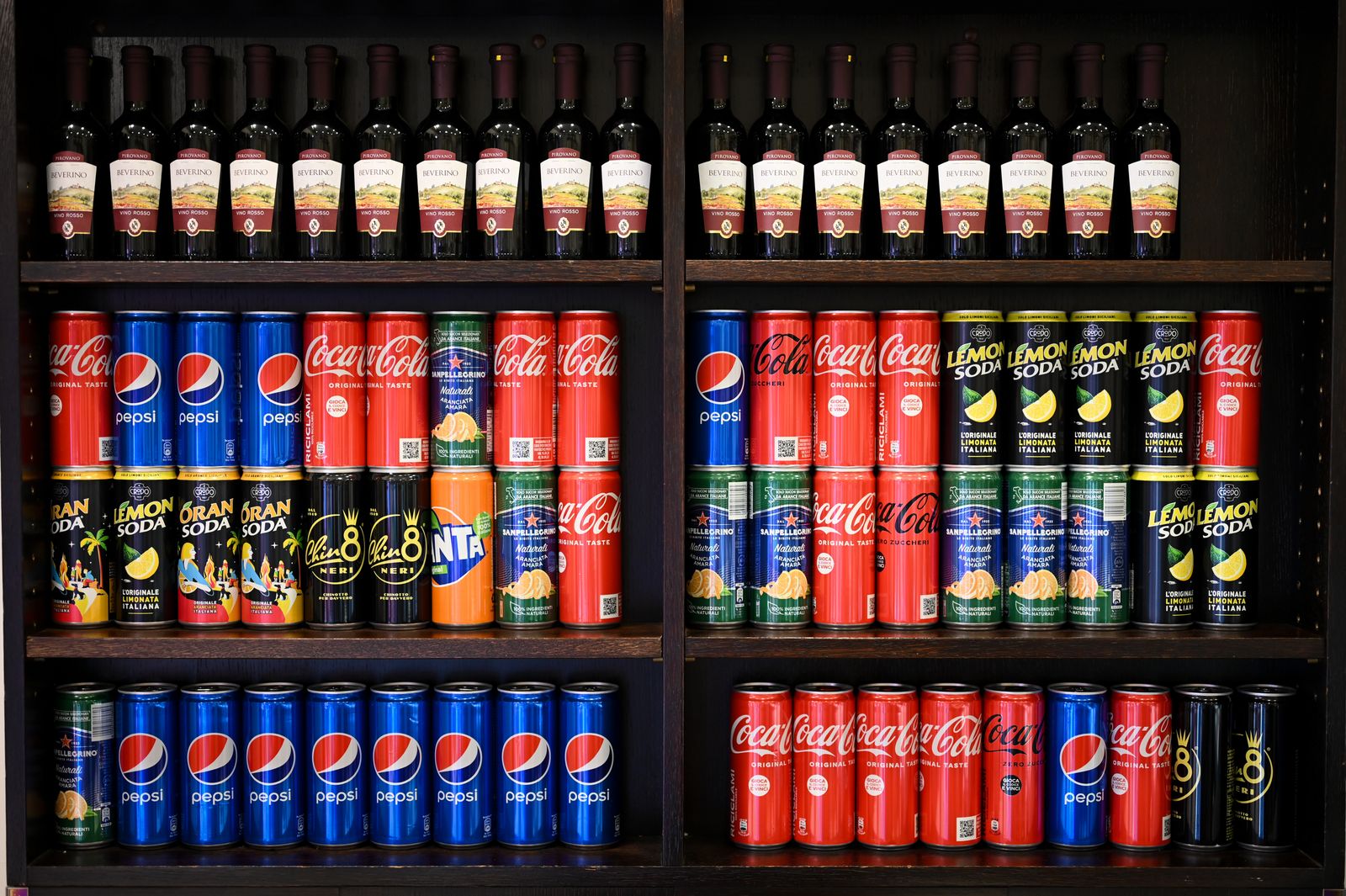 Botellas y latas de bebidas en un estante de supermercado