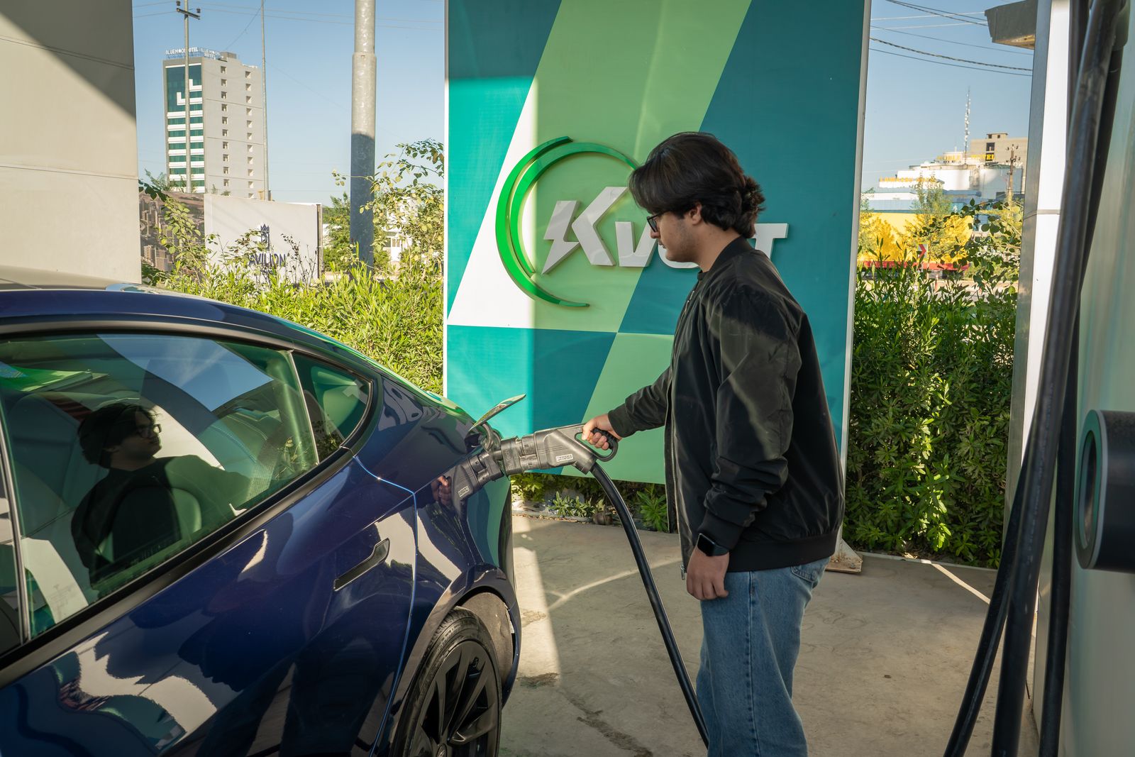 Automóvil eléctrico conectado a una estación de carga en un entorno urbano