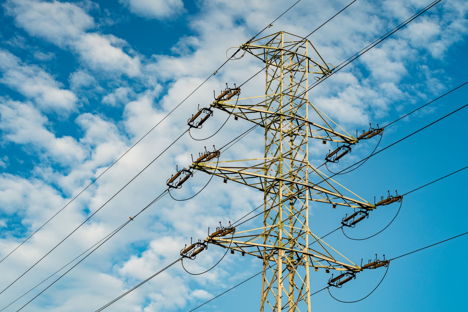 Torres de alta tensión y líneas eléctricas al atardecer junto a una ciudad