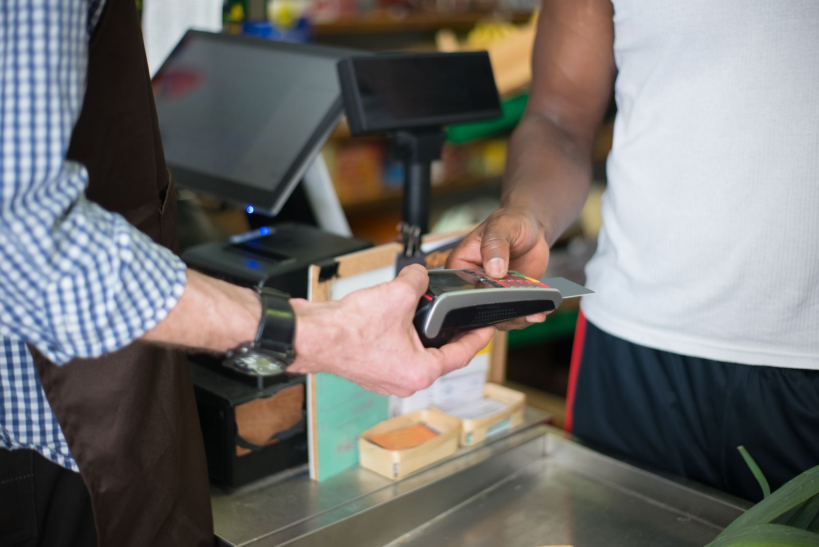 Persona realizando un pago con tarjeta de crédito en una terminal en un comercio
