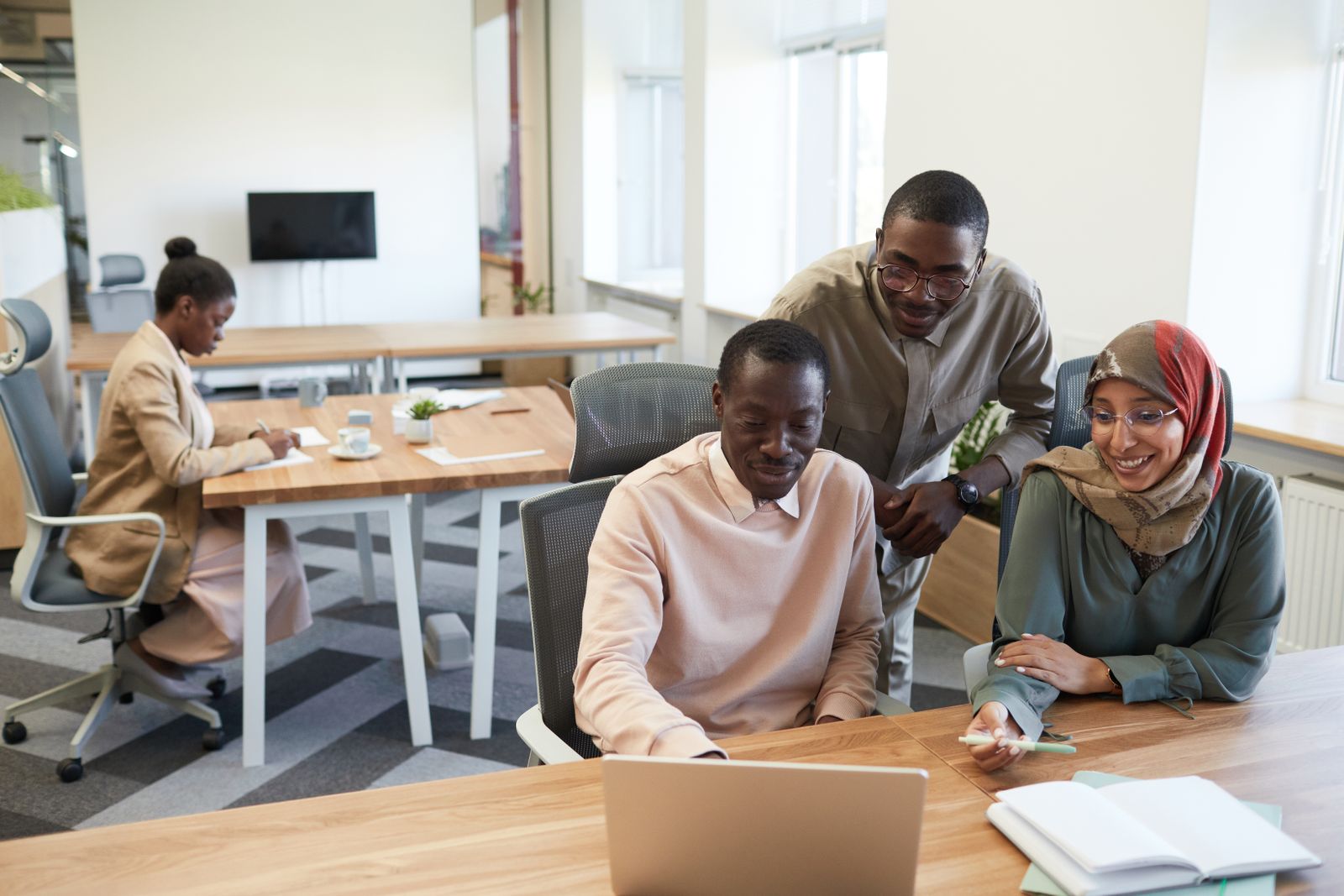 Equipo de trabajo en una oficina de startup tecnológica colaborando frente a computadoras