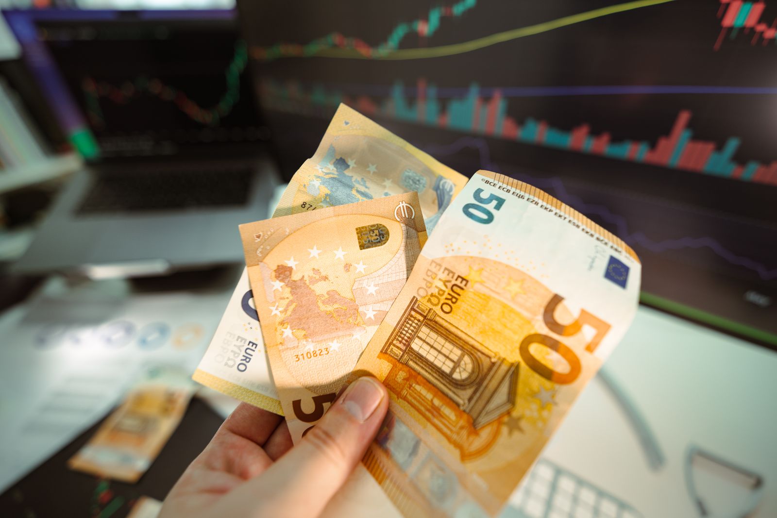 Billetes y una pantalla de cotizaciones cambiarias que representan el mercado de divisas