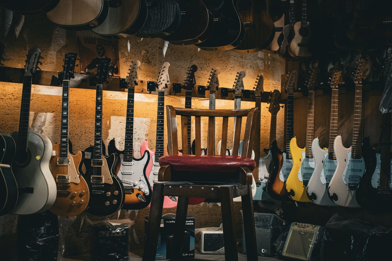 Guitarra acústica sobre una silla de madera en un ambiente sobrio y con luz tenue.