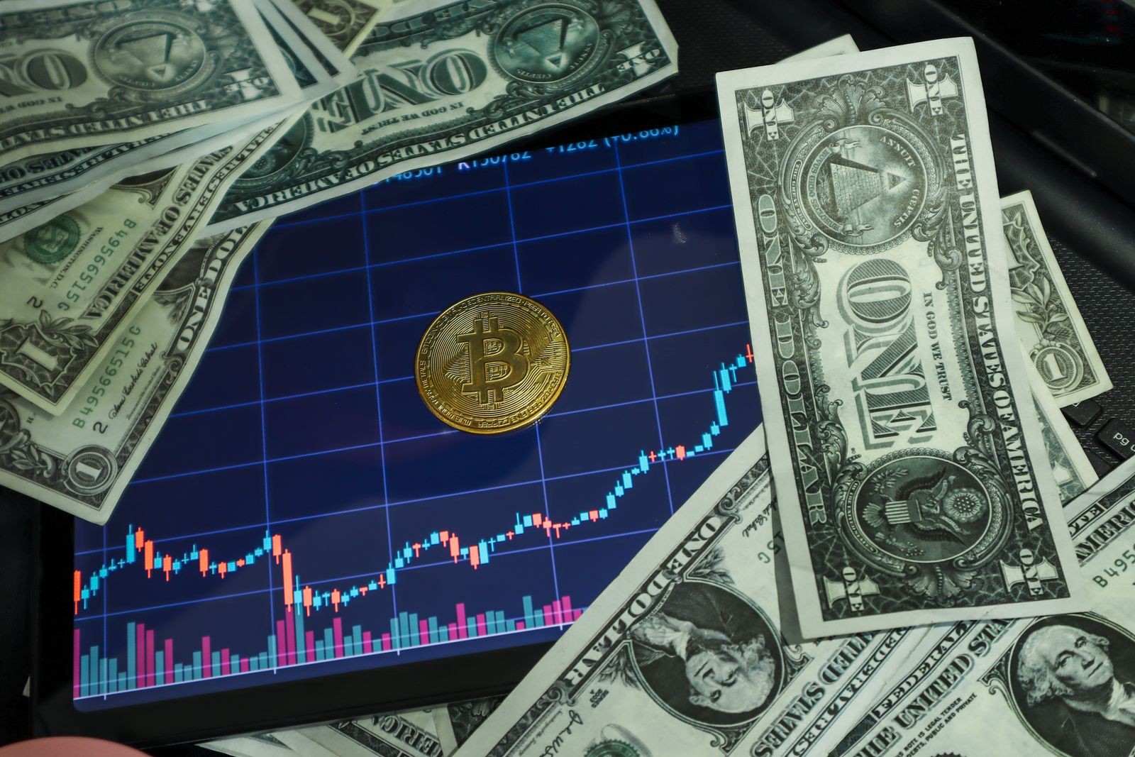 Billetes de dólar y monedas sobre una mesa con gráficos financieros