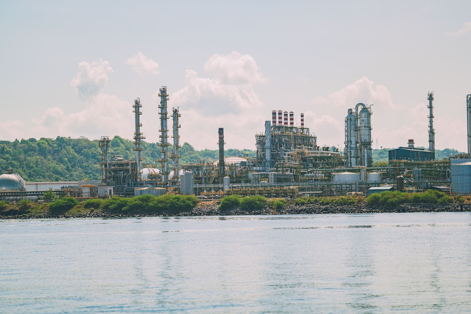 Instalaciones industriales de refinería de petróleo con torres y tuberías al atardecer